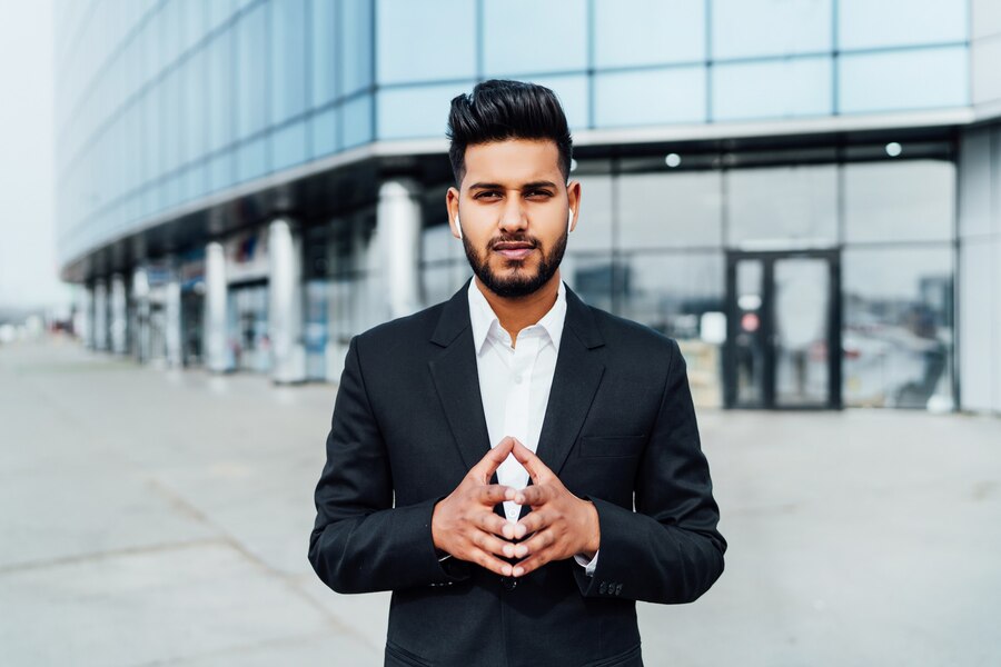 portrait-serious-smiling-modern-indian-man-near-office-building_496169-2890